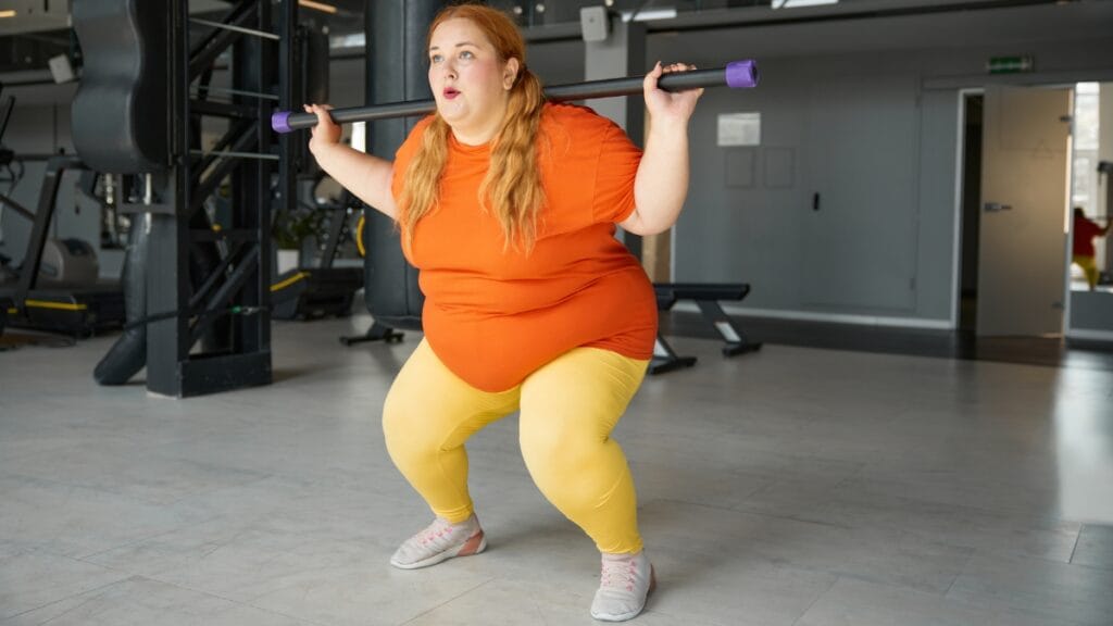 Woman in a plus size workout romper lifting weights in the gym