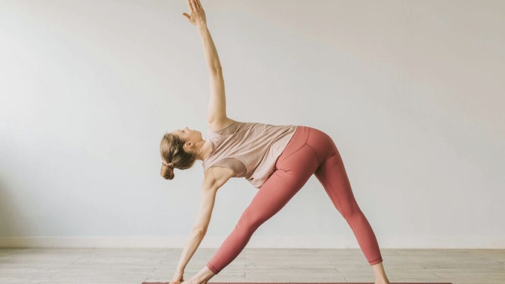 "Woman performing yoga in plus size yoga pants, stretching in a side angle pose."