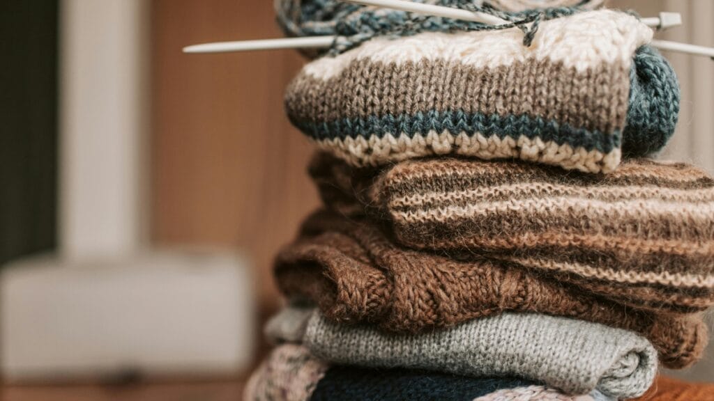 This image showcases a collection of hand-knitted scarves, hats, and gloves in various earthy tones, ideal for winter fashion. The intricate patterns and textures make these accessories both stylish and functional, offering warmth and comfort during the colder months.