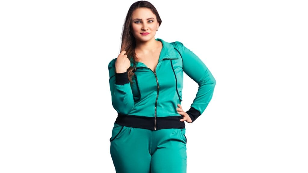 Short fat woman wearing a teal tracksuit, standing confidently with a slight smile