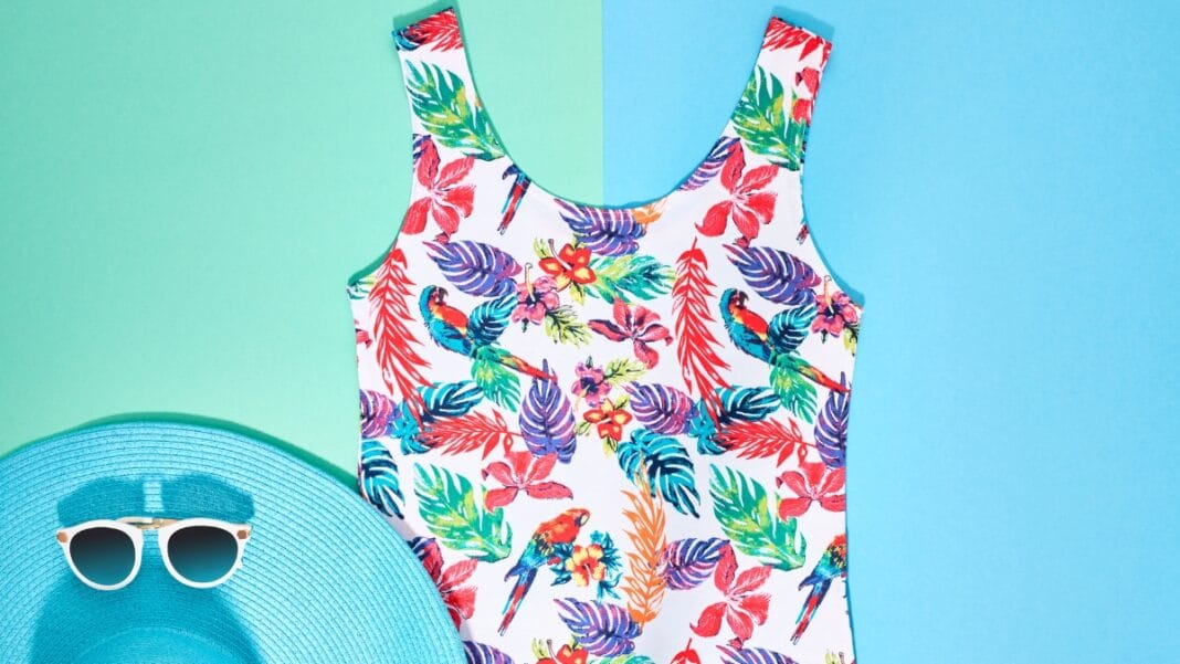Women’s floral swim tankini displayed on a blue background with sunglasses