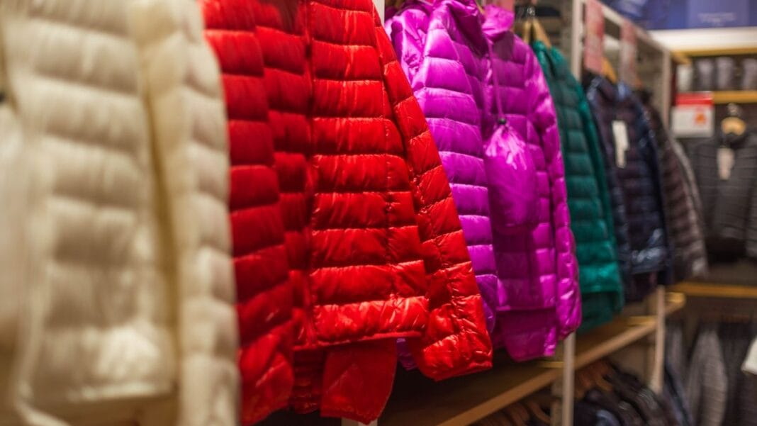 A variety of colorful puffer jackets in different colors hanging in a store.