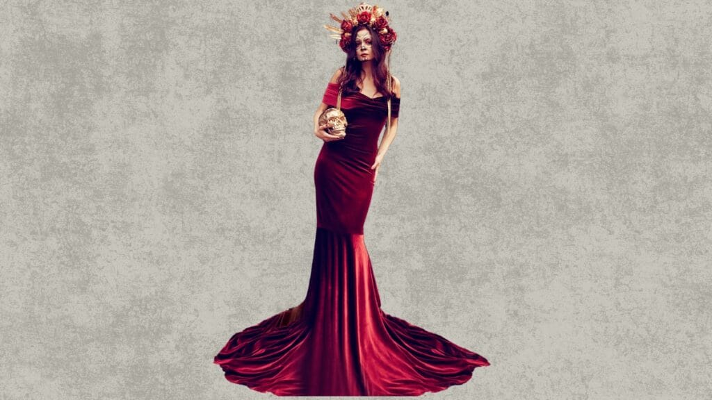 Woman in a red velvet fall dress surrounded by autumn leaves, holding a skull