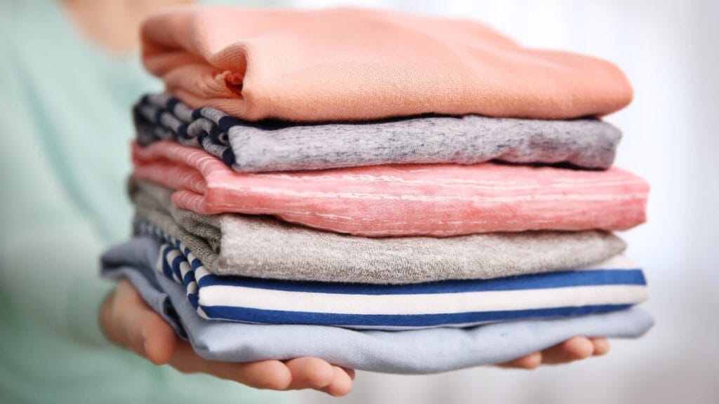 A stack of folded t-shirts in pastel colors, made from some of the best clothing materials.
