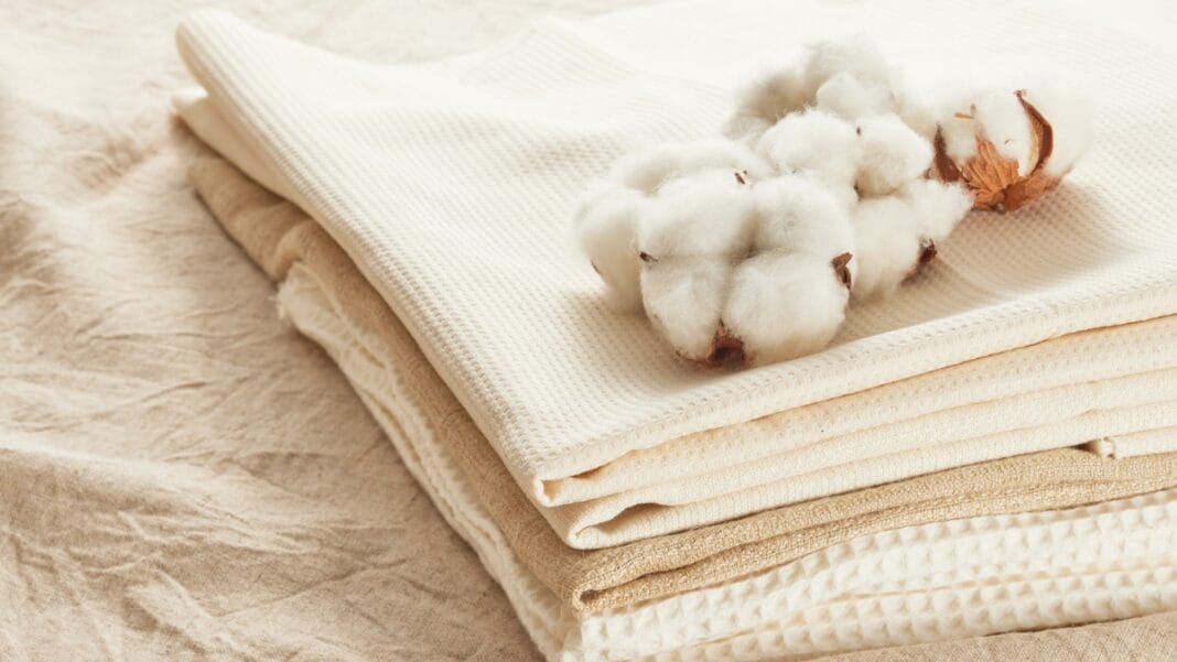 Cotton balls placed atop neatly folded cotton fabrics in soft beige and cream tones