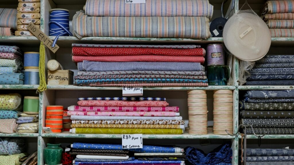 A variety of cotton fabric rolls neatly stacked on shelves, showcasing different textures and patterns