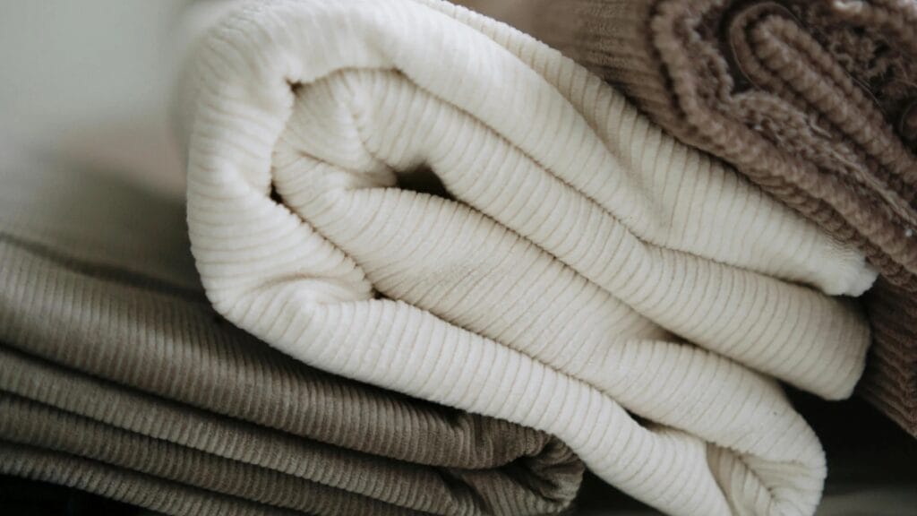 Neatly rolled fabrics in varying neutral tones showcasing different cloth compositions.