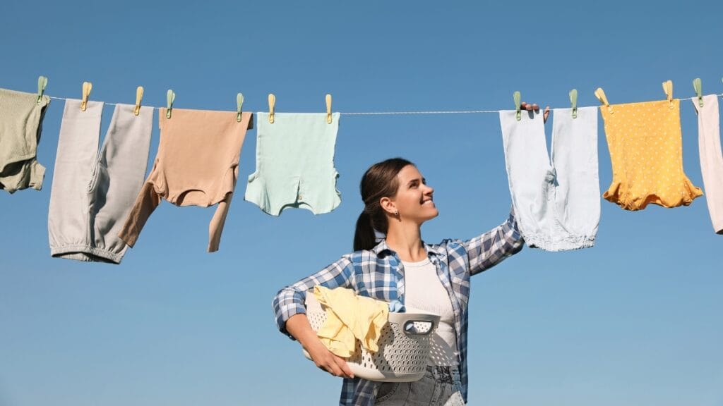 Person hanging clothes washed on delicate on a clothesline outdoors, showcasing careful drying techniques