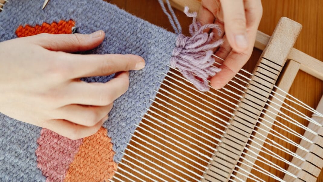 Person weaving colorful coarse fabric on a loom with close-up hands
