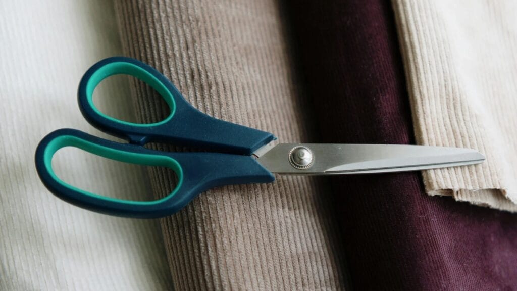 Scissors cutting through different fabric types, including cotton and polyester materials.
