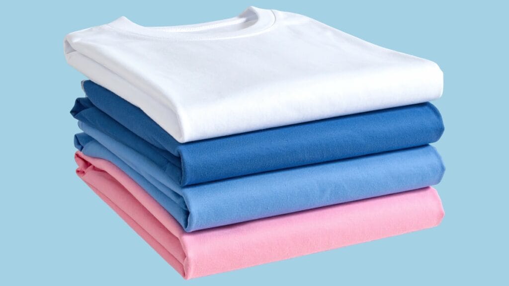 A stack of t-shirts made from cotton or polyester fabric in various colors.