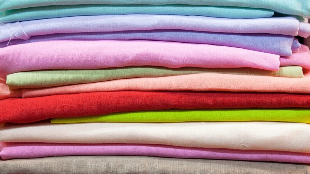 A stack of colorful cotton fabrics showcasing various types of cotton materials in soft hues