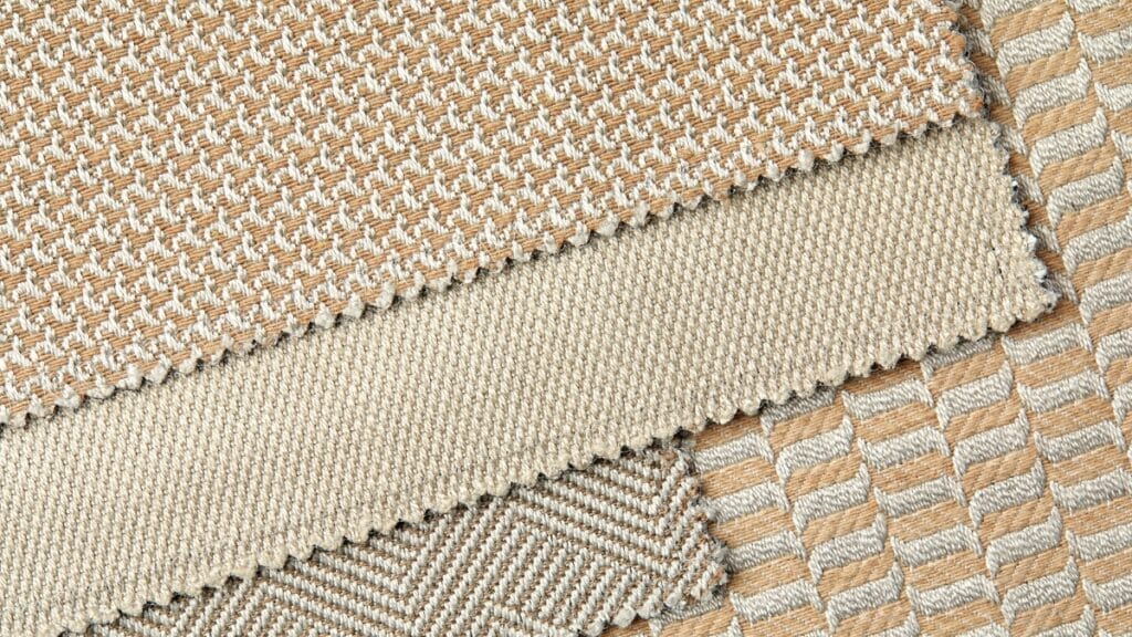 A collection of colorful fabric strips arranged vertically to demonstrate the straight fabric grain in different colors like blue, orange, and brown.