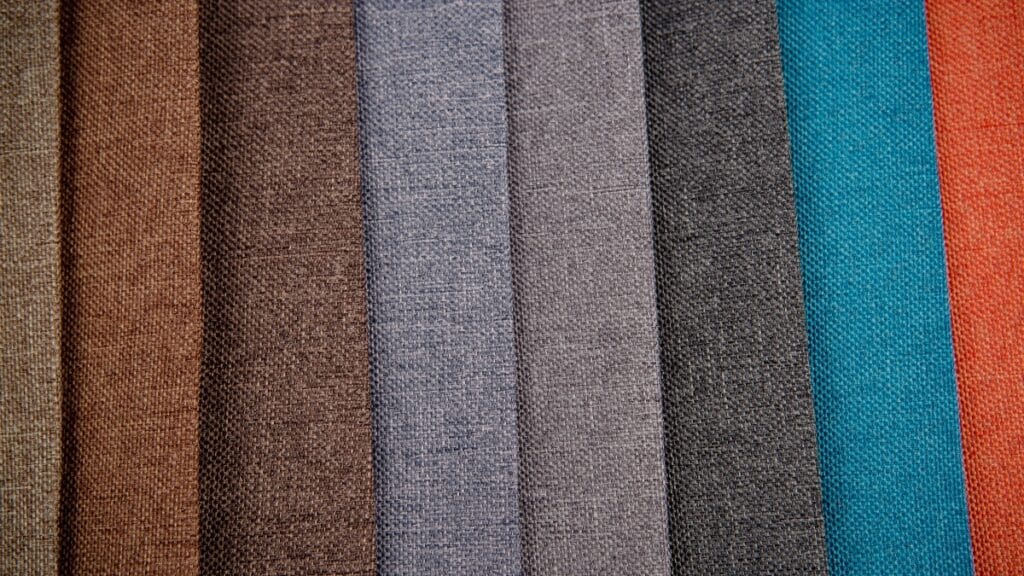 A close-up view of three beige and cream fabric swatches showing the diagonal and vertical texture of the fabric grain