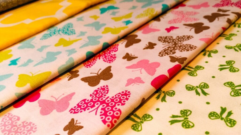 A variety of fabric prints with butterfly and bow patterns in pastel colors