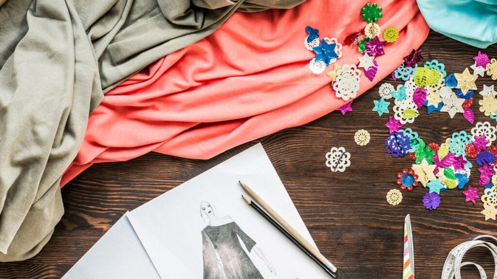 Colorful fabric and embellishments spread on a wooden surface for fashion design