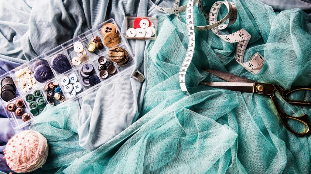 Sewing tools and fashion materials like buttons and fabric laid out on a table