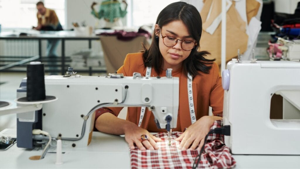 Sewing machine fabric being stitched on a sewing machine by a seamstress in a well-lit workspace