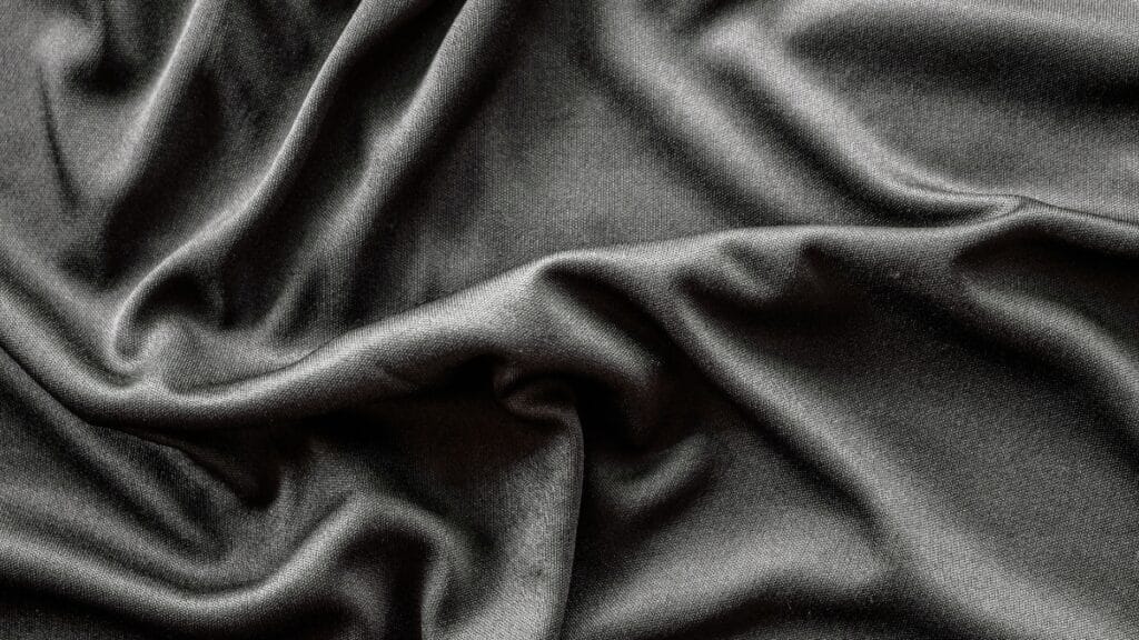 Black two-way stretch fabric with smooth folds, highlighting its stretchability