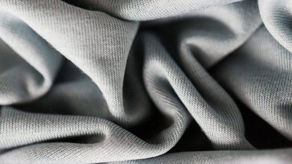 Light grey two-way stretch fabric close-up showing its smooth texture and flexibility
