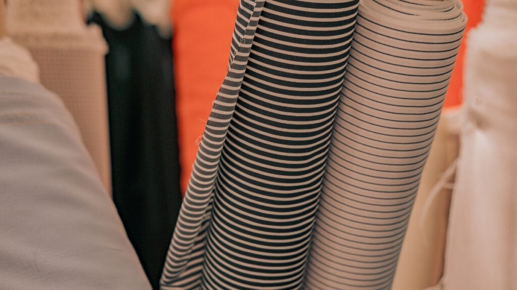Rolls of stretch fabric in various colors and patterns, including striped designs