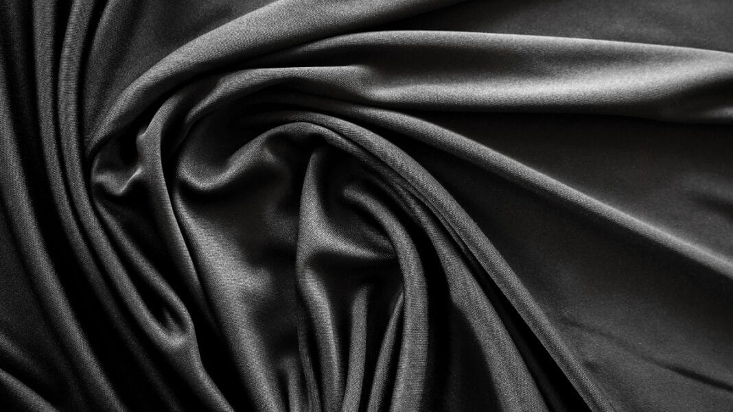 Close-up of smooth black stretch fabric with soft folds, ideal for clothing and activewear