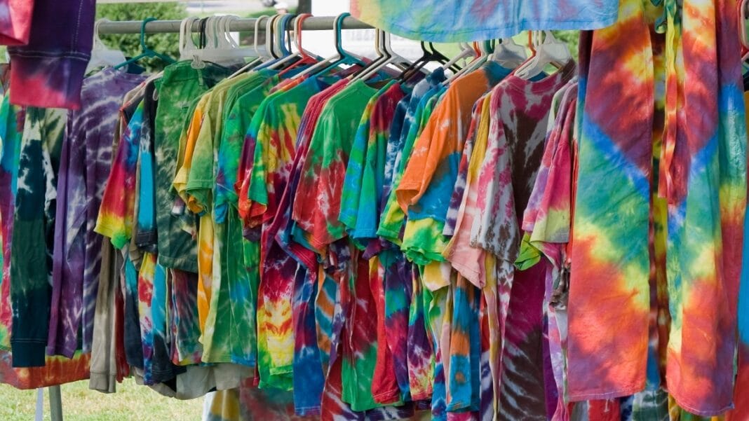 A collection of colorful tie dye t-shirts hanging on a rack with various color combos