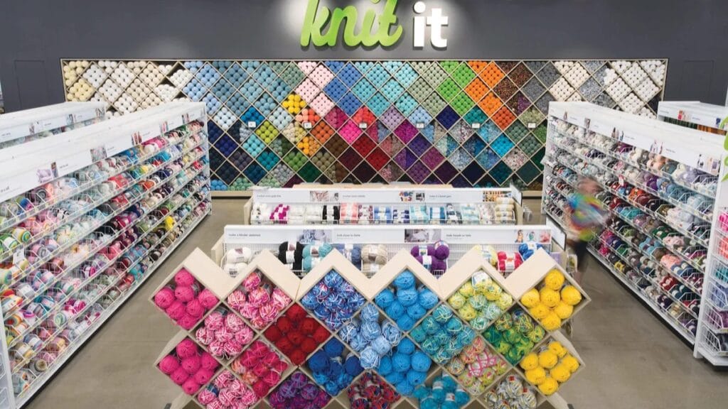 Large diamond-pattern wall display filled with yarn skeins in every color.