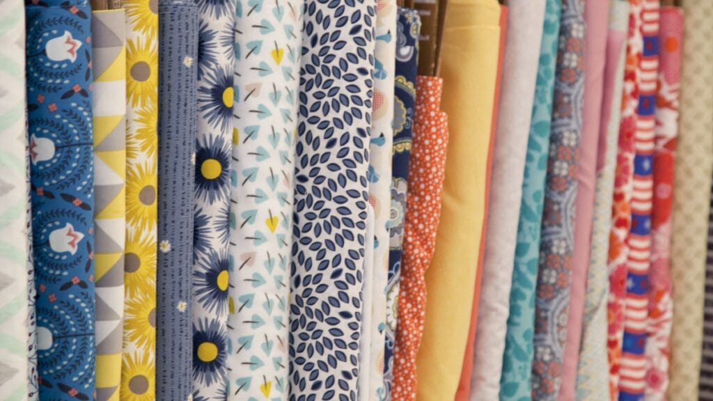 A colorful row of rolled fabrics with various patterns from florals to geometric designs.