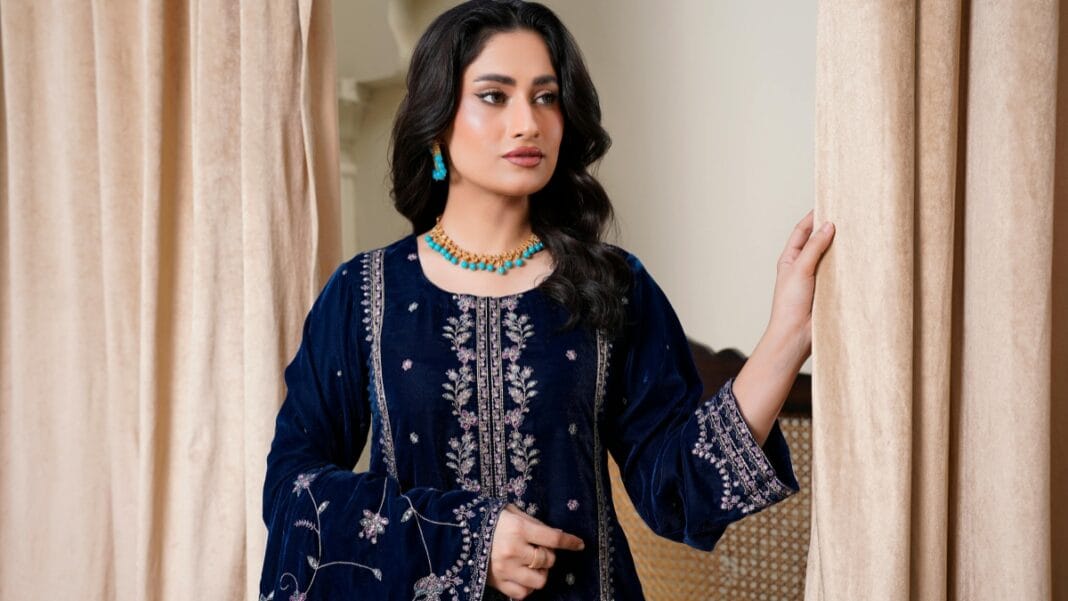 Elegant woman wearing a navy embroidered dress with matching turquoise jewelry indoors.