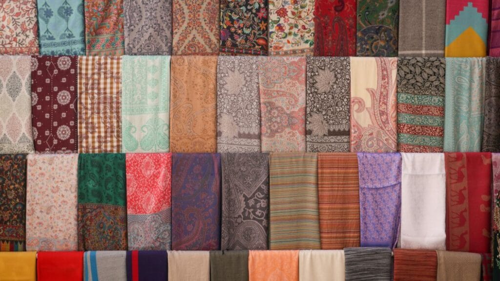 Colorful assortment of folded fabrics with floral, paisley, and geometric patterns displayed in rows