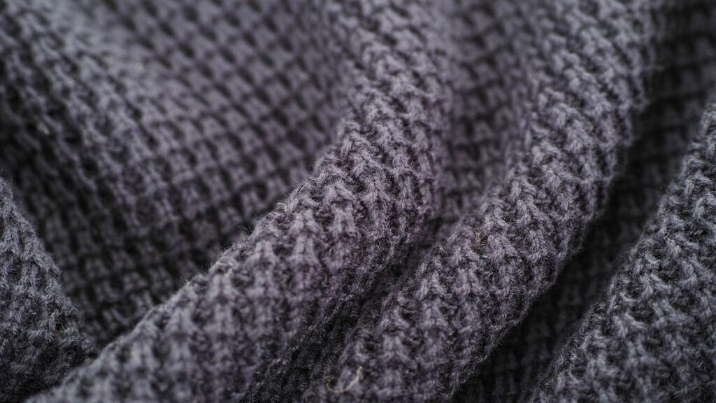 Close-up of gray knitted fabric with a soft, textured weave and visible loops