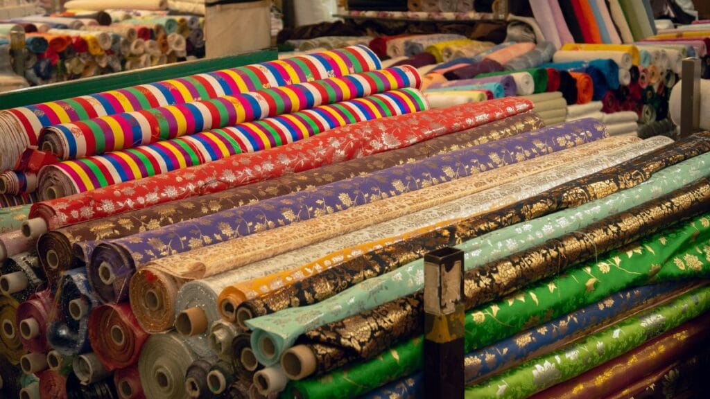 Rolls of colorful patterned fabric neatly stacked in a textile shop display