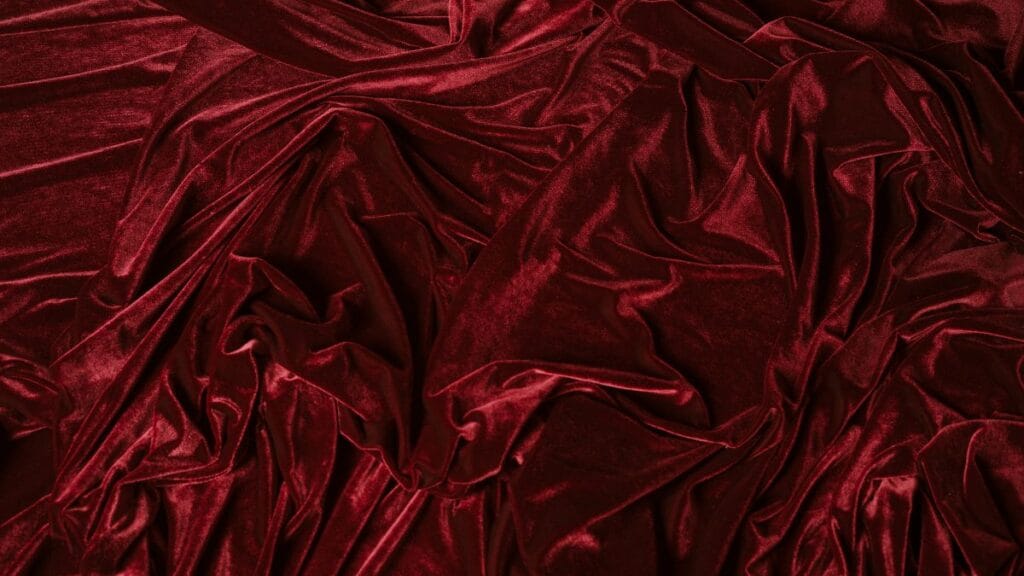 Rich red velvet fabric with soft folds and a smooth, shiny texture