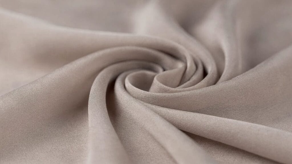 Close-up of soft viscose fabric folded in a swirl, showing smooth texture and drape.