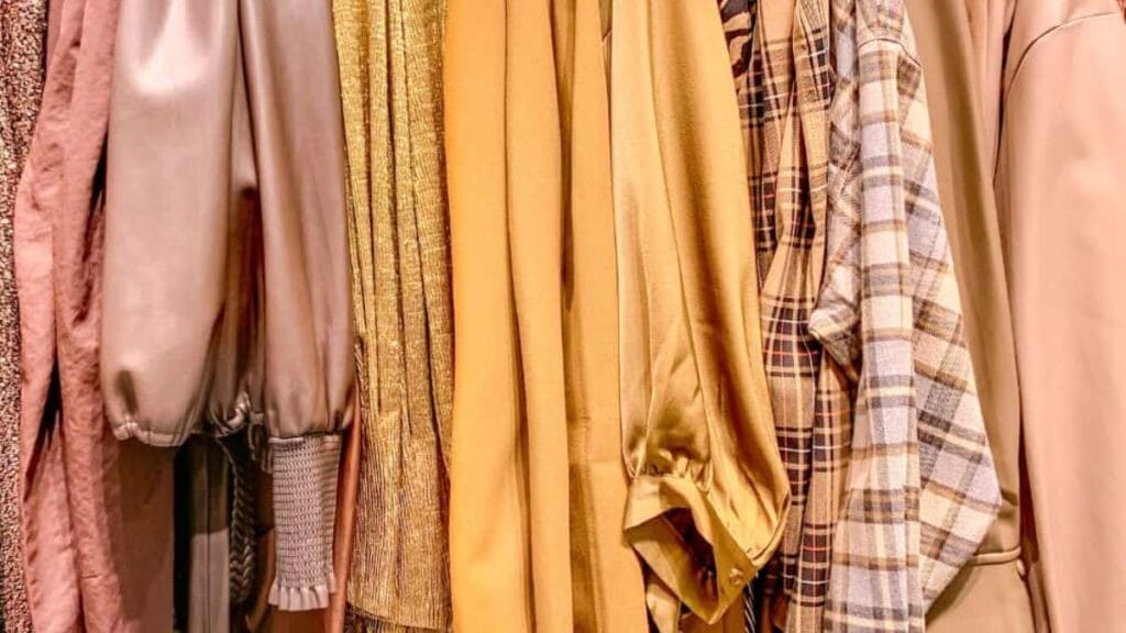 Close-up of neutral-toned clothing on a rack showing soft viscose fabric textures and styles.
