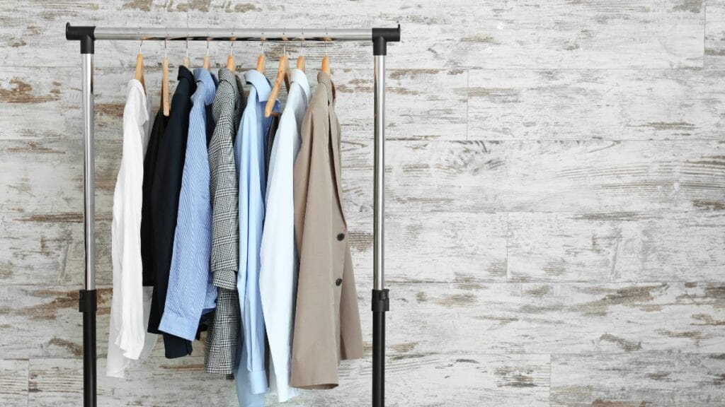 A clothing rack displaying several shirts in neutral colors—white, black, gray, and beige.