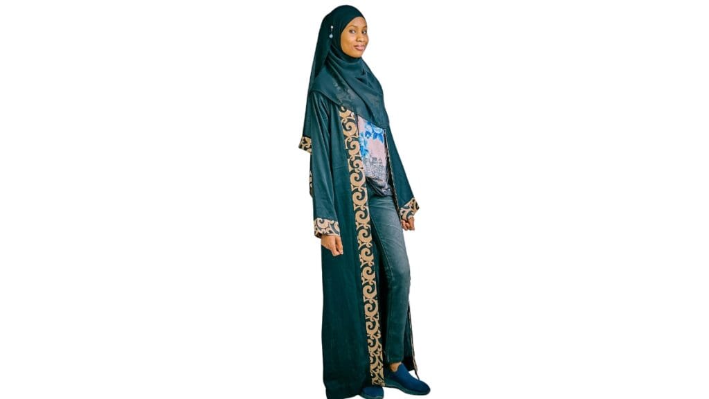 A full-length studio photo of a model wearing a dark green long tunic with a matching head covering and gold-and-blue decorative trim along the front and sleeves.