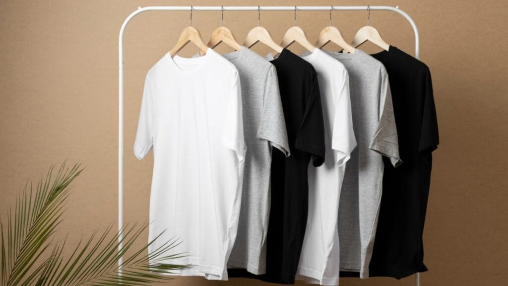 A row of short-sleeve tunic shirts in white, gray, and black hanging on a clothing rack.