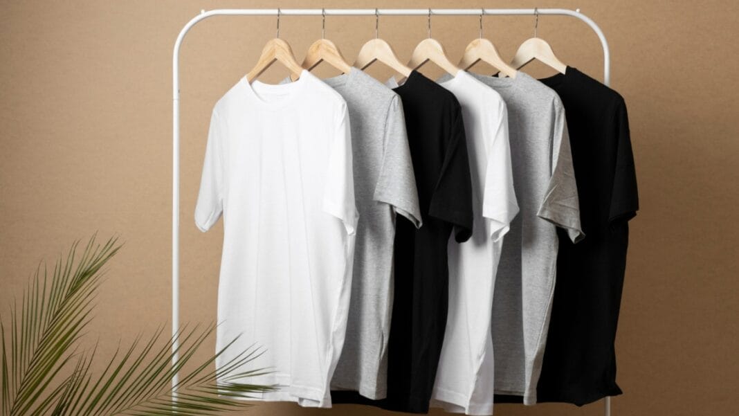 A row of short-sleeve tunic shirts in white, gray, and black hanging on a clothing rack.