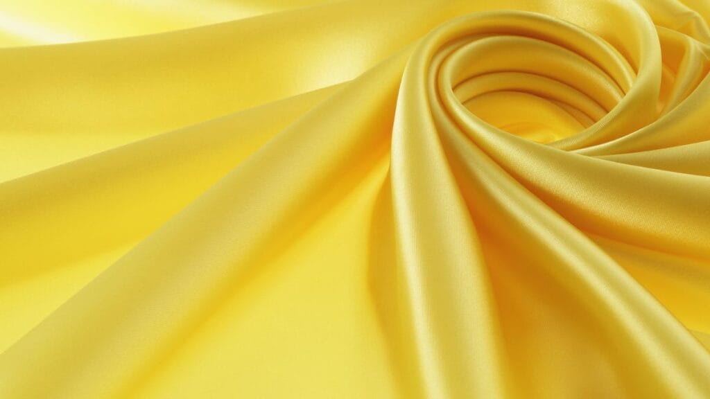 Smooth yellow satin fabric elegantly folded into soft curves with a glossy finish