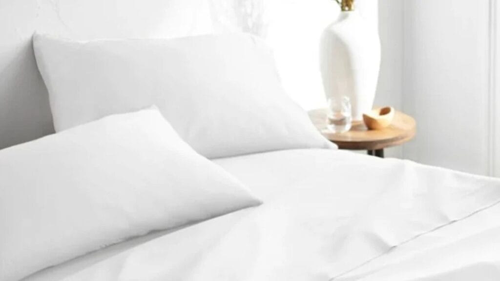 White bed with soft pillows and bamboo viscose bedding in a clean, minimal bedroom setting.