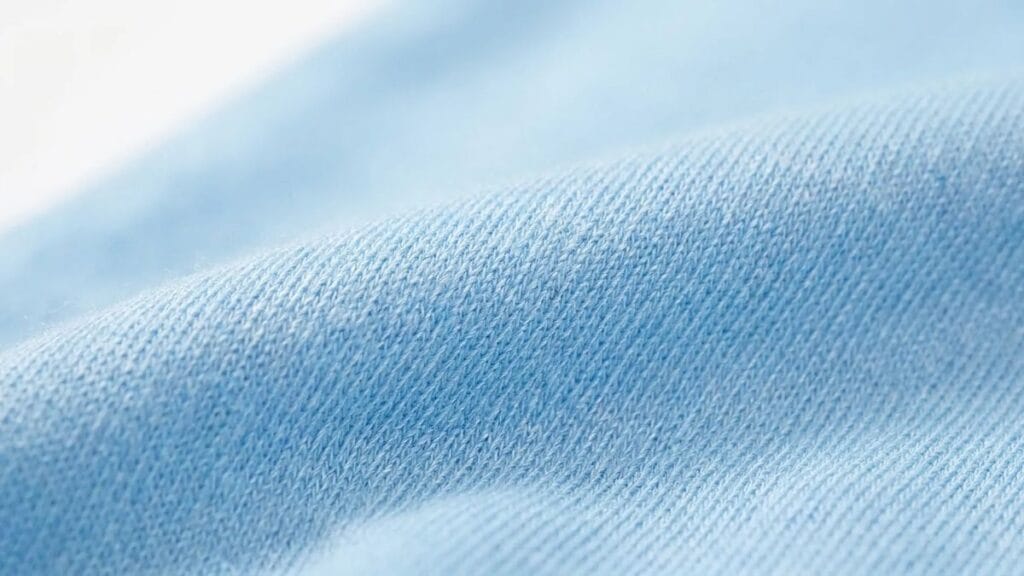 Close-up of soft blue viscose fabric showing fine knit texture and smooth surface.