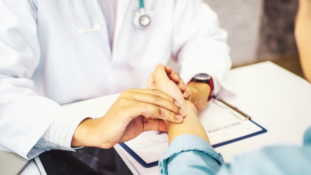 Doctor holding a patient’s hand in a healthcare setting.