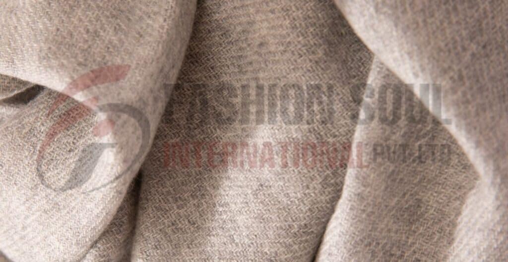 Close-up of a soft light beige fabric, highlighting its woven texture and wool blend composition. Types of wool blends