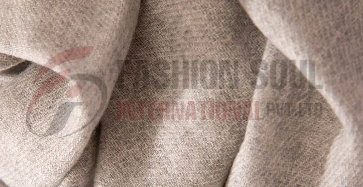 Close-up view of a textured wool fabric in light gray, showcasing a herringbone pattern.