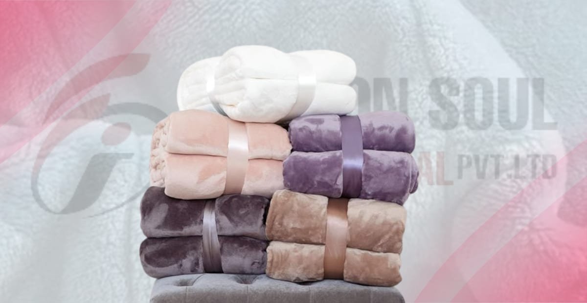 A stack of soft, fleece blankets in various shades of white, peach, purple, and brown, neatly tied with ribbons, set against a blurred background. fleece fabric types