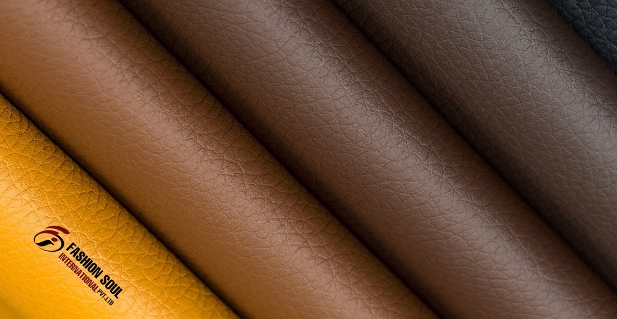 Close-up of four rolls of vegan leather in various shades, including yellow, light brown, dark brown, and black, with a logo in the corner.