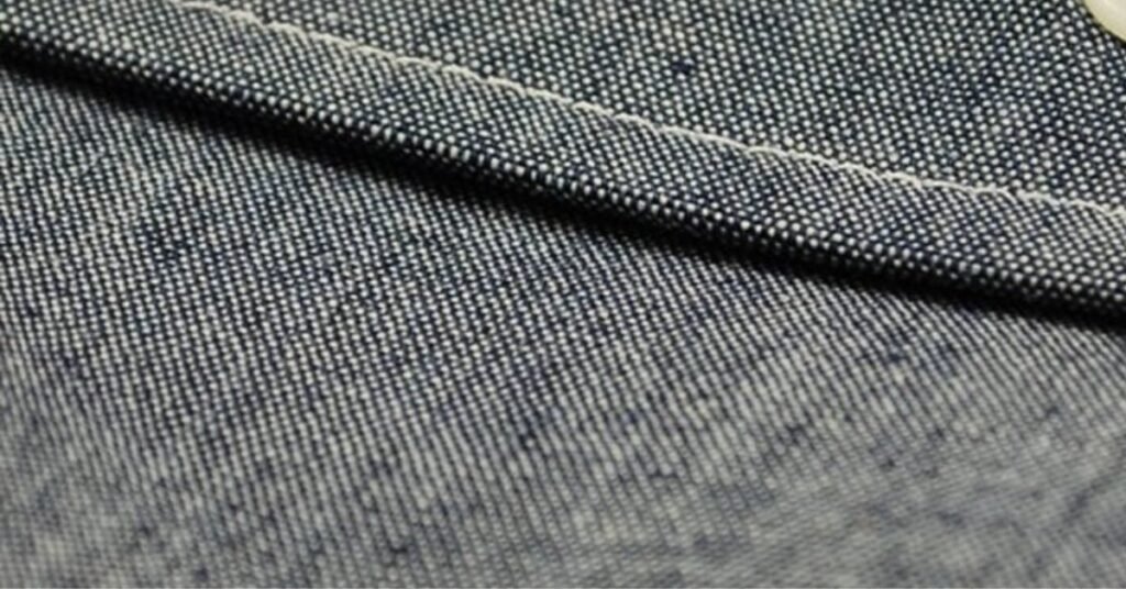 Close-up view of chambray fabric showing its fine weave, soft texture, and signature blue and white color contrast.