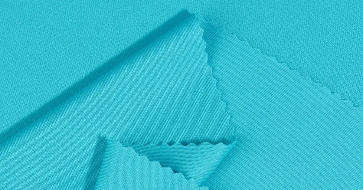 Close-up of turquoise interlock fabric showcasing its smooth, double-knit texture and fine finish.